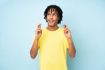 Young african american man isolated on blue background with fingers crossing and wishing the best