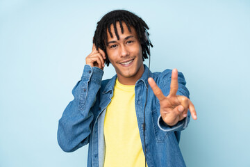 Young african american man isolated on blue background listening music and singing