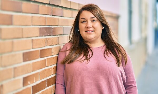 Young hispanic plus size woman smiling happy standing at the city.