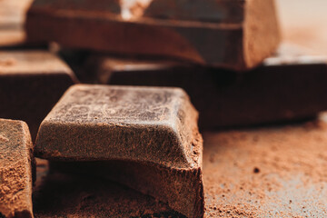 Chocolate bar and chopped chocolate cubes on dark background, close-up view