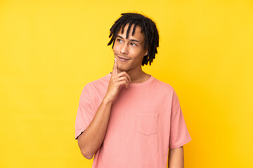 Fototapeta na wymiar Young african american man isolated on yellow background thinking an idea while looking up