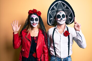 Couple wearing day of the dead costume over yellow showing and pointing up with fingers number six...