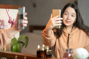 Selective focus. Happy smiling girl takes a selfie in front of the mirror. Blurred image
girl talking on a video call on the phone while sitting in front of the mirror.