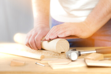 Obraz na płótnie Canvas Schreiner schleift mit Schleifpapier ein Stück Holz in der Werkstatt