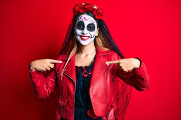 Woman wearing day of the dead costume over red looking confident with smile on face, pointing oneself with fingers proud and happy.