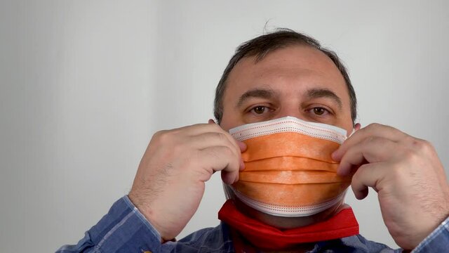 person takes turns wearing medical masks of different colors. man in colored surgical masks. compliance with the regime of permanent wearing of the mask. 100 days Masking Challenge