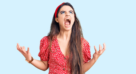 Fototapeta na wymiar Brunette teenager girl wearing summer dress crazy and mad shouting and yelling with aggressive expression and arms raised. frustration concept.