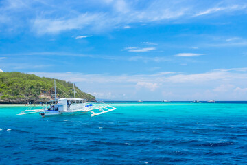 Tropical lagoon of Sumilon island, Philippines. Traditional filipino banca boat in azure crystal clear water.