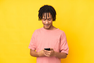 Young african american man isolated on yellow background sending a message with the mobile