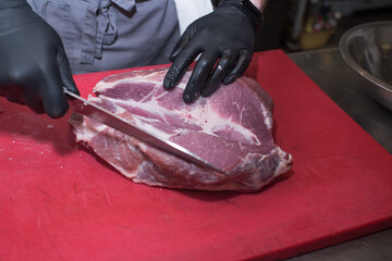 Cutting pork meat. Chef working in the kitchen in a pub