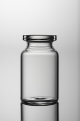 Medicine glass jar, capacity for liquid medicines with an open neck without stopper. Close up shot on a gray background