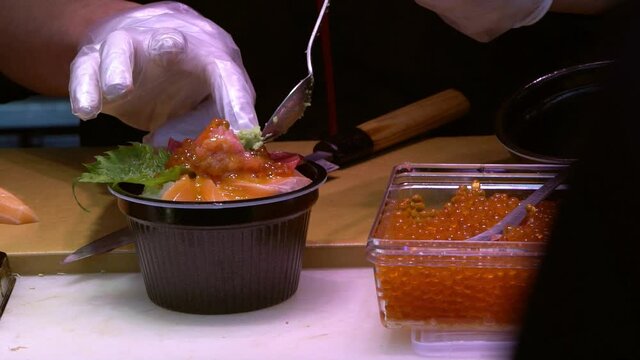 Slowmotion of chef preparing fresh shushi dish with wasabi, cutting with knife on cutting board in restaurant. Man cooked popular japanese food at famous marketplace in Tokyo. Healthy food Concept-Dan