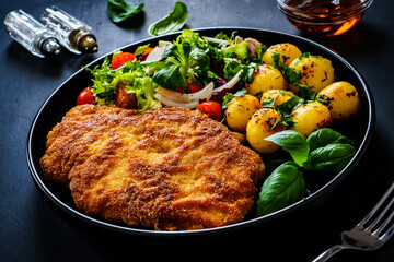 Breaded fried pork chop, French fries and vegetables on white background
