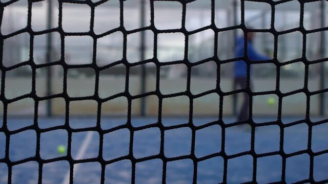 Slow motion through grid view of paddle tennis man playing on blue court outdoors. One caucasian padle player sportman hitting the ball. Racquet sport game Concept.-Dan