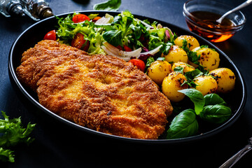 Breaded fried pork chop, French fries and vegetables on white background
