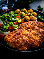 Breaded fried pork chop, French fries and vegetables on white background
