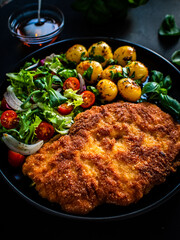 Breaded fried pork chop, French fries and vegetables on white background
