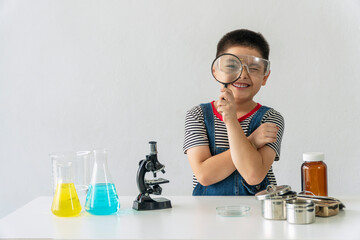 Education scientists concept. Little kid scientific boy holding magnifying in his hand front view...