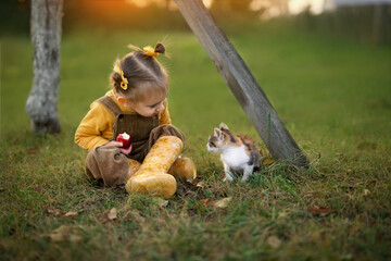 little girl eating red apple. girl sitting with a kitten. the girl wants to feed the cat with an apple.  Friendship with pets. World Pets Day. International Homeless Animals Day