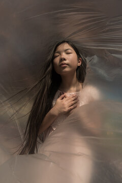 Conceptual fineart portrait of a girl covered by and wrapped in plastic outside during the pandemic