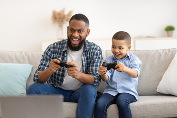 Black Dad And Son Play Videogame Together On Weekend Indoors © Prostock-studio