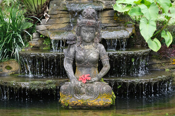 Fototapeta na wymiar Indonesia Bali - Ubud Handmade Balinese stone statue with red Hibiscus flower