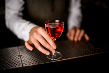 beautiful glass with drink stands on bar counter the man's hand holds it