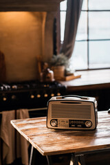 a vintage radio player stands on a wooden table in the apartment. Daylight from the window illuminates the room. Cozy kitchen playing classical music.