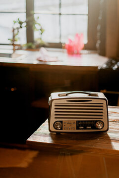 vintage radio player stands on a wooden table in a bright apartment. Daylight from the window illuminates the room. Cozy kitchen playing classical music.
