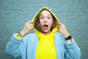 Closeup portrait of shocked girl with brown eyes and open mouse look at the camera holding yellow...