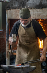 Rural blacksmith working metal with hammer on the anvil in the forge