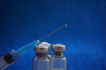medical ampoules and syringe on blue background