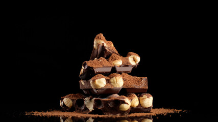 chocolate. stack of chocolate bar with nuts and cocoa powder on black background. dark chocolate...