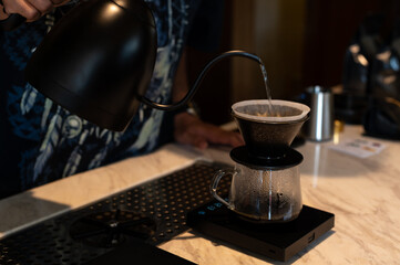 Making pour over coffee with hot water from a kettle called drip coffee