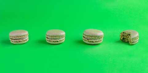 green macarons lined up one bitten with green background