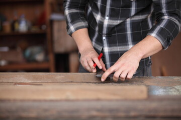 Carpenter, joiner is working in the workshop. Man at work on wood.Image of mature carpenter in the workshop,furniture making concept.