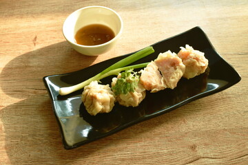 steamed Chinese dumpling stabbing minced pork and shrimp or dim sum dipping soy sauce on plate