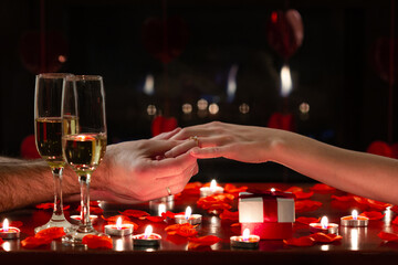 Boyfriend asking her girlfriend to marry him with a shiny ring on her finger. Engagement scene for Valentine’s Day celebration during romantic dinner. Concept about lifestyle, proposal and love. 
