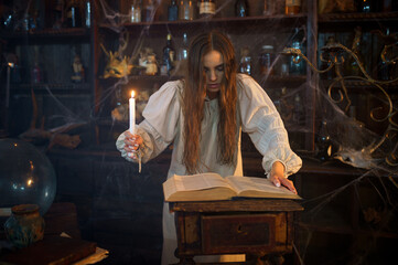 Demonic woman with candle reads book of spells