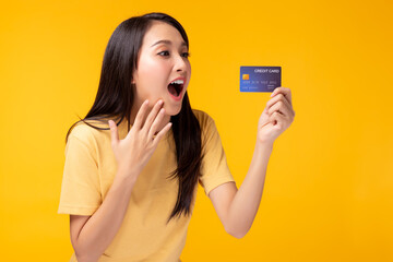 Young woman holding credit card with facial expression. Beautiful customer girl get surprised when get credit card Use for your advertising Yellow background. Internet banking, online shopping concept