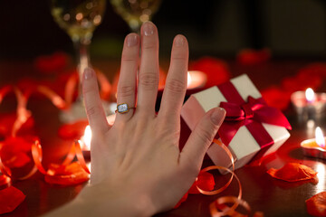 Close up of woman’s hand wearing engagement shiny ring on her finger. Valentine’s Day celebration scene. Concept about lifestyle, events and love.