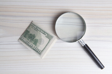 Hundred dollar bill and magnifying glass