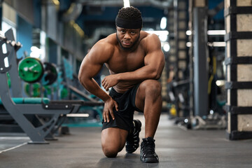 Fototapeta na wymiar Tired african american shirtless bodybuilder resting while workout