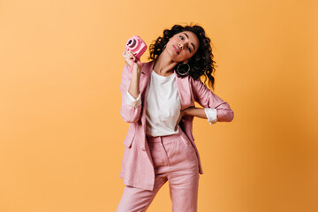 Adorable female photographer standing with hand on hip. Studio shot of elegant woman with camera.