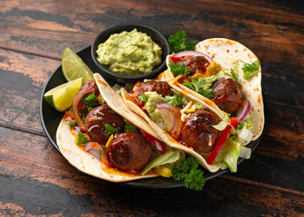 Meat free beetroot and pea protein meatballs taco wraps with avocado guacamole, sweet chilli sauce and lime wedges