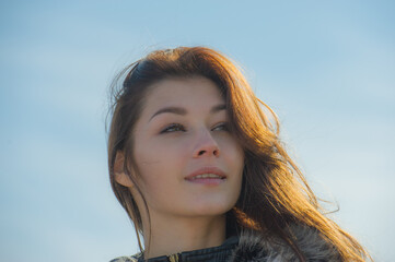 Portrait of a pretty girl with fluttering long hair in the wind on a sunny day.
