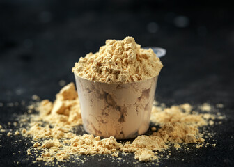 Scoop of Pea Vegan protein powder on dark rustic background. Sport nutrition.