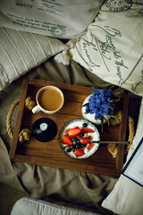 granola with yoghurt  strawberries and blueberries on a wooden tray with a cup of coffee with milk