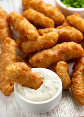 Battered Haddock fish, mini fingers with mashed peas, tartar sauce on white wooden board