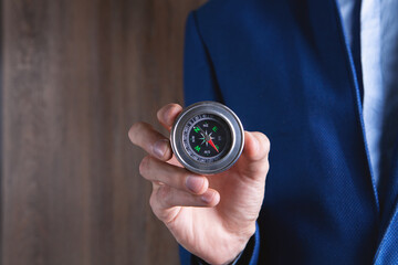 businessman holds a metal compass in his hands.